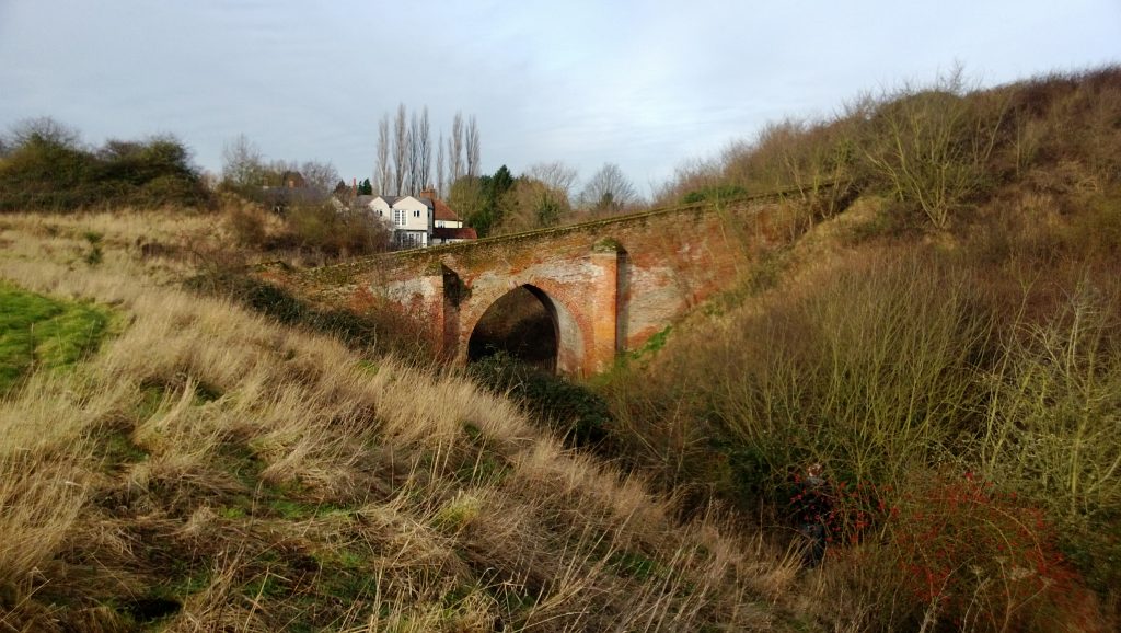 A brick bridge leading up to a motte and crossing a castle ditch