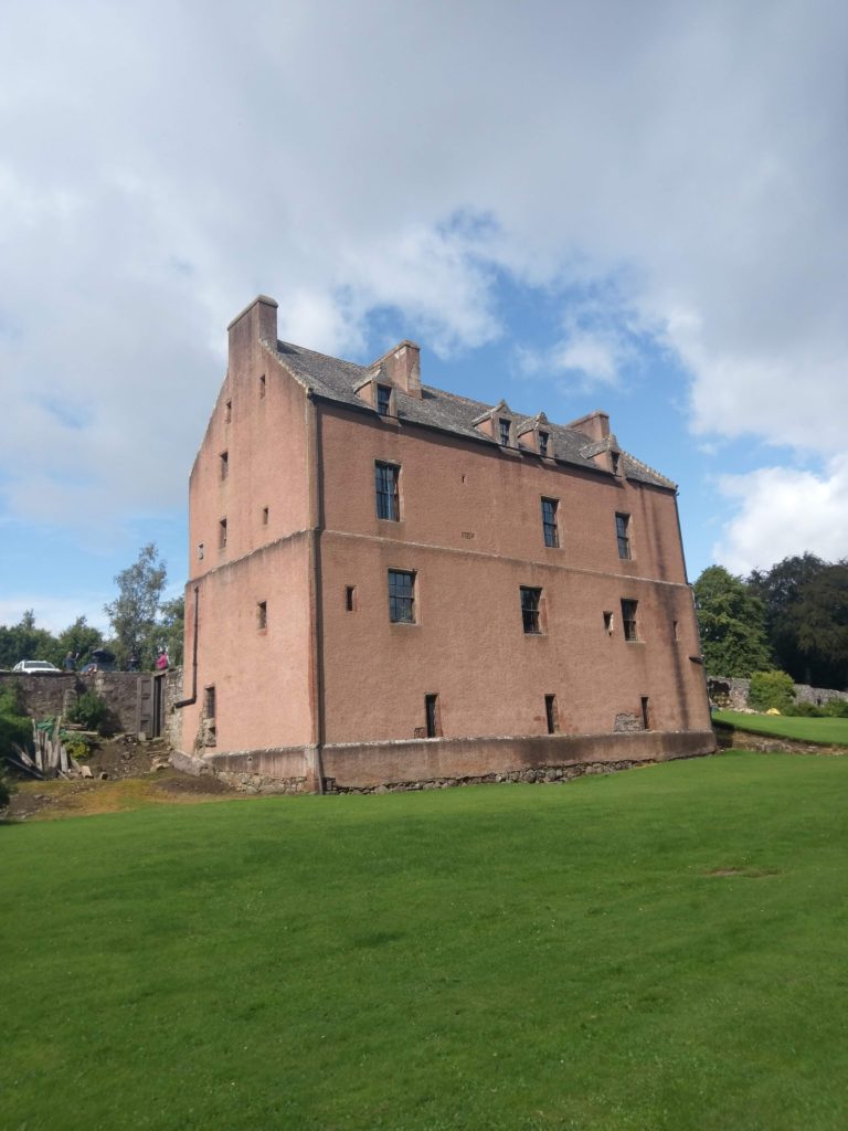 A large red squarish building surrounded by grass.