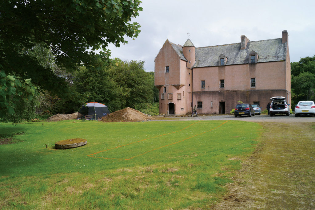 A pinkish stone tower in the background with grassy ground in the front.