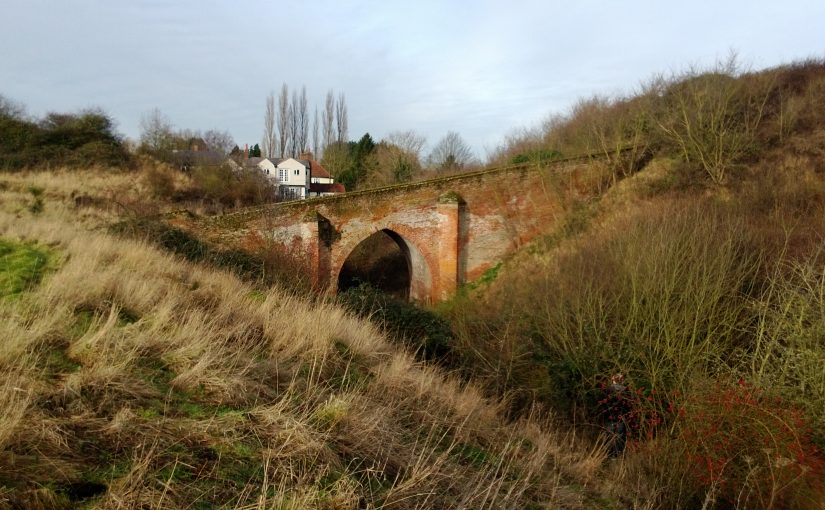 A brick bridge leading up to a motte and crossing a castle ditch